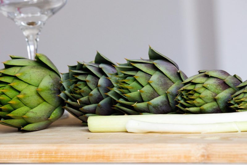 green artichokes on a cutting board ready for cooking