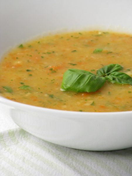 creamy yellow soup topped with green basil leaves