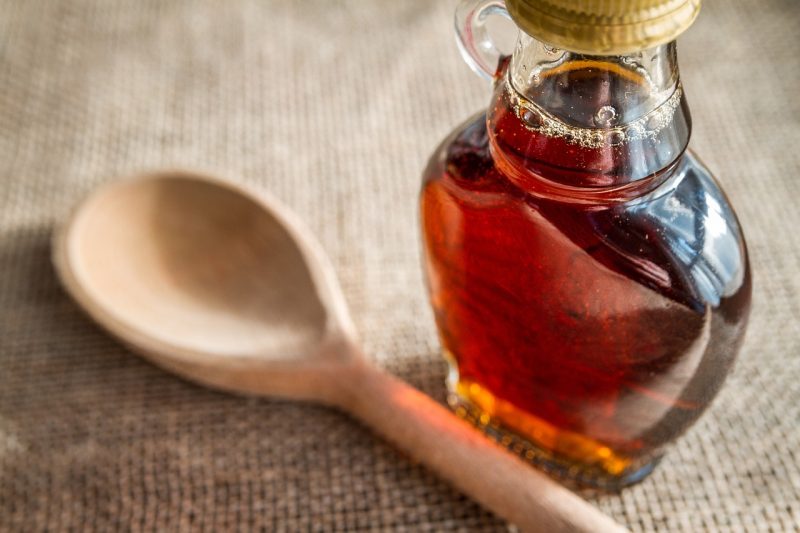 maple syrup in a glass jar and a wooden spoon