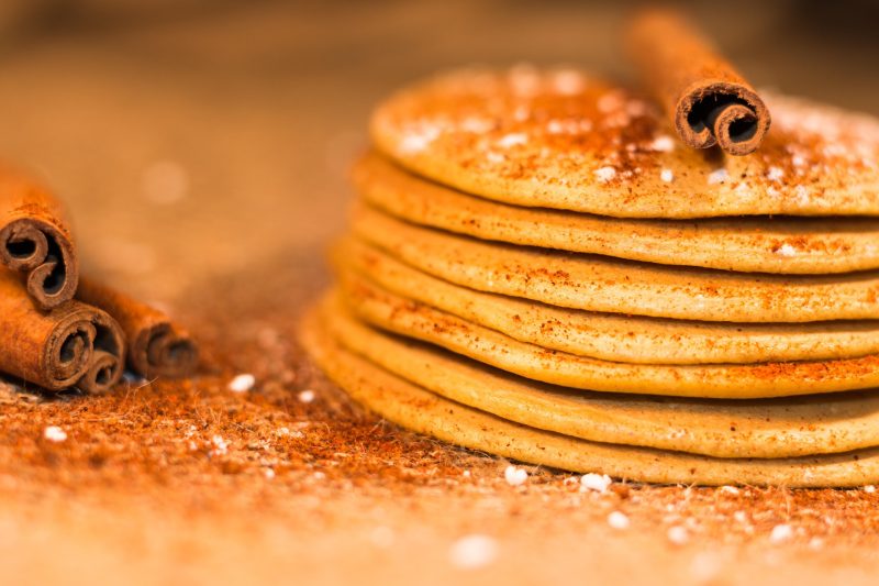 stack of golden pancakes and a curl of cinnamon bark