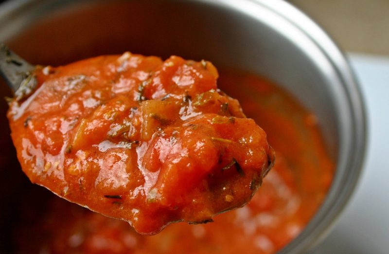 homemade tomato sauce on a spoon over a pot