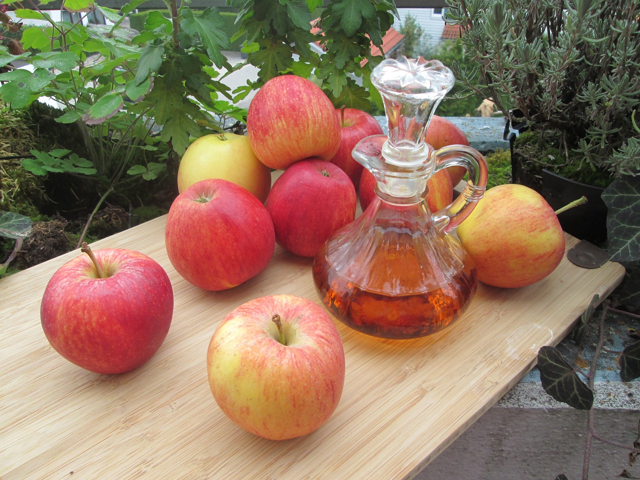 cruet of apple cider vinegar on a board with apples